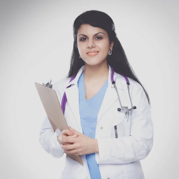 Молодая врач женщина со стетоскопом стоя на белом фоне — стоковое фото