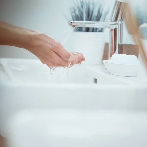 Jonge vrouw wassen haar gezicht met schoon water in badkamer — Stockfoto