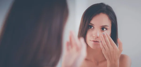 Attraktive junge Frau cremt ihr Gesicht ein — Stockfoto