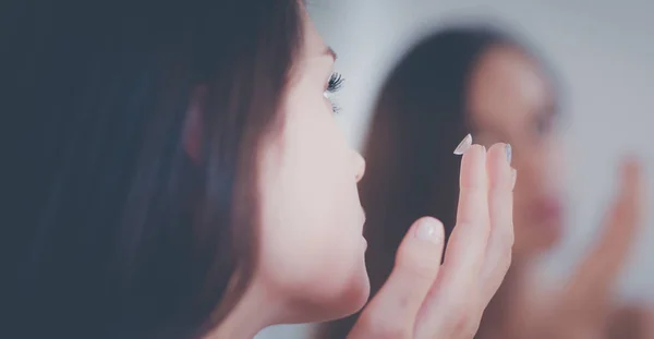 Attraente giovane donna che applica la crema sul suo viso — Foto Stock
