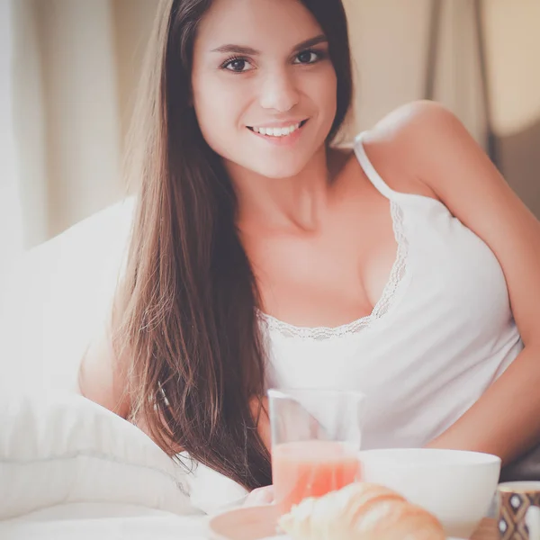 年轻女子坐在床上与一杯牛奶 — 图库照片