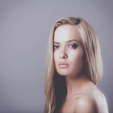 Gri arka planda izole edilmiş güzel bir kadının portresi.