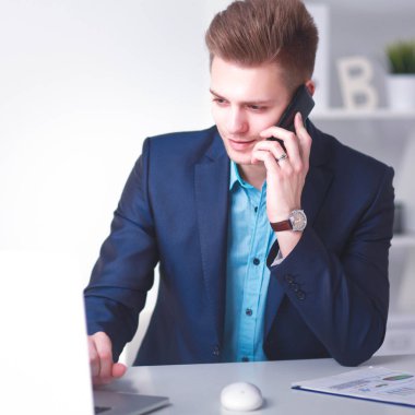 Genç işadamı ofiste çalışıyor, masada oturuyor.