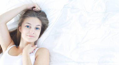 Yatakta rahat ve mutlu bir şekilde yatan güzel bir genç kadın.