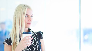 Ofiste bir fincan kahve ayakta tutan işkadını