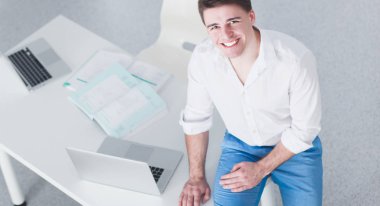 Genç işadamı ofiste çalışıyor, masada oturuyor.