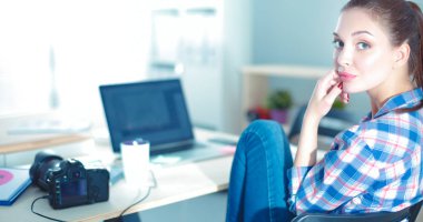 Masada dizüstü bilgisayarla oturan kadın fotoğrafçı.