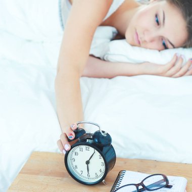 Güzel genç bir kadın, rahat ve mutlu bir şekilde yatakta uzanıyor.