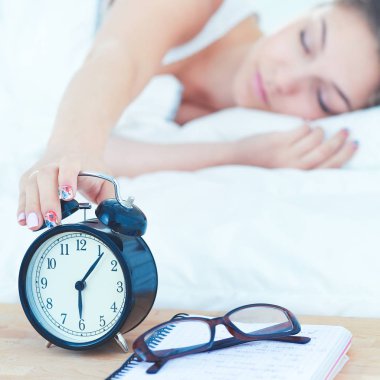 Güzel genç bir kadın, rahat ve mutlu bir şekilde yatakta uzanıyor.