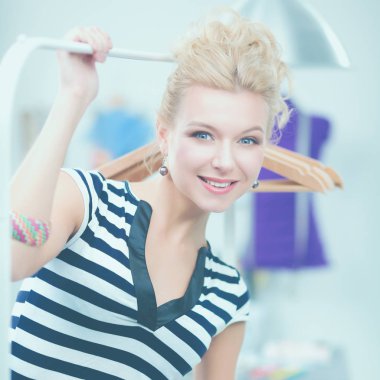 Raf ofiste askıları ile yakınındaki güzel genç stilist