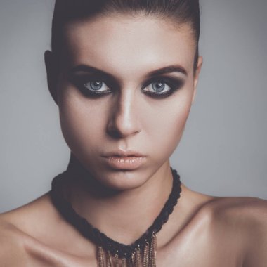 Gri arka plan üzerinde duran güzel genç kadın