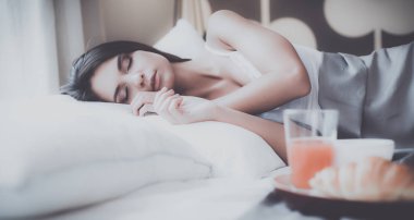 bir bardak süt ile yatakta oturan genç kadın