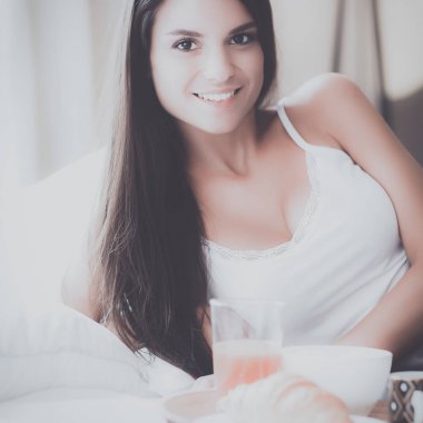 bir bardak süt ile yatakta oturan genç kadın