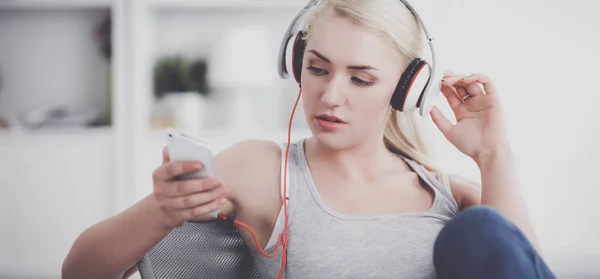 Jonge mooie vrouw thuis zitten op de bank en luisteren muziek — Stockfoto