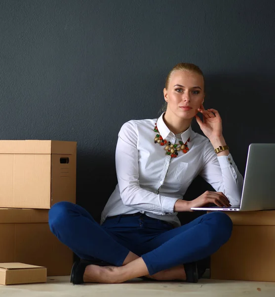 Kobieta siedzi na podłodze w pobliżu pudełek z laptopem — Zdjęcie stockowe