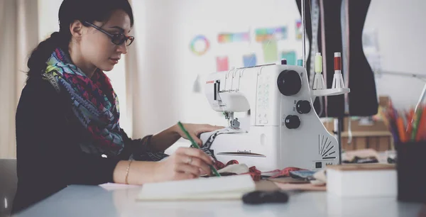 Mujer joven cosiendo sentado en su lugar de trabajo —  Fotos de Stock