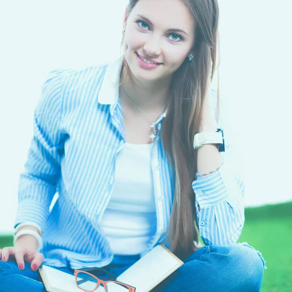 Jonge vrouw zitten met boek op gras — Stockfoto