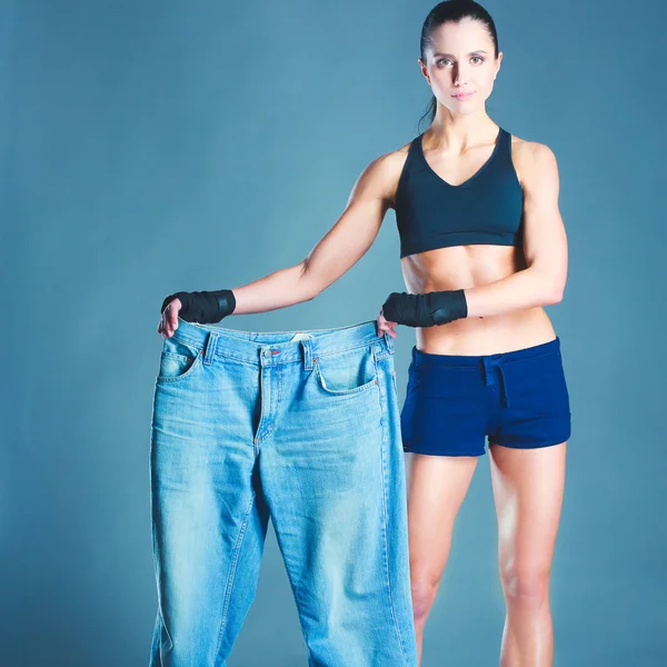 Joven mujer fitness mostrando que sus viejos pantalones vaqueros —  Fotos de Stock