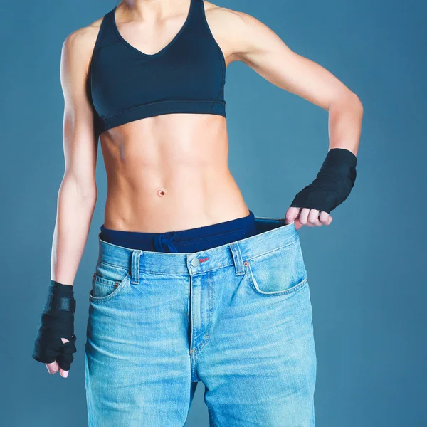 Jovem mulher fitness mostrando que seus jeans velhos — Fotografia de Stock