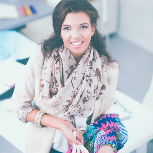 Glimlachende vrouwelijke mode-ontwerper zit aan het bureau — Stockfoto