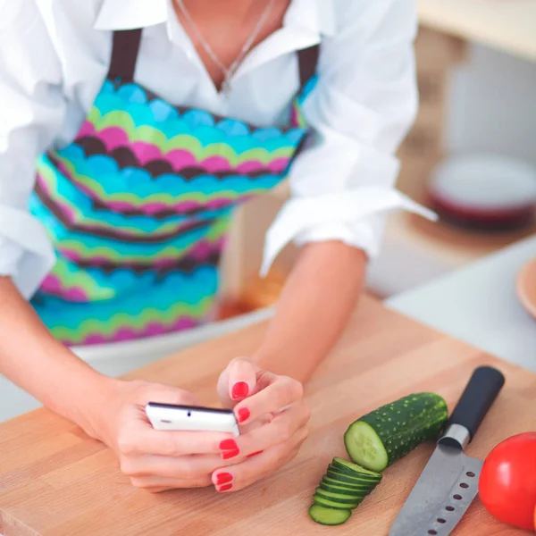Mosolygó nő fogja a mobilját a konyhában. — Stock Fotó