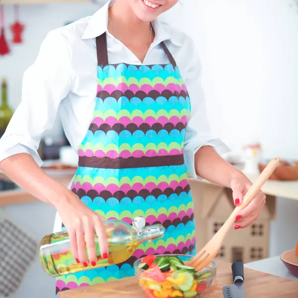 Улыбающаяся молодая женщина смешивает свежий салат на кухне — стоковое фото