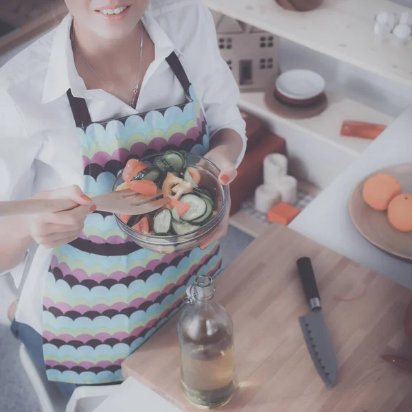 Lachende jonge vrouw mengen van frisse salade in keuken — Stockfoto