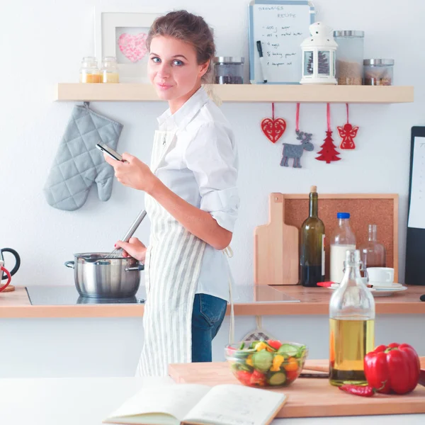 Portret van een lachende vrouw met telefoon in de keuken thuis — Stockfoto