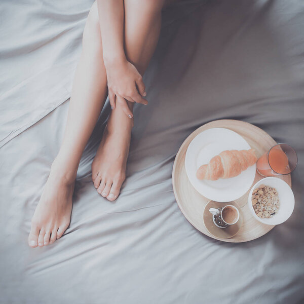 Молодая женщина сидит в постели с чашкой молока
