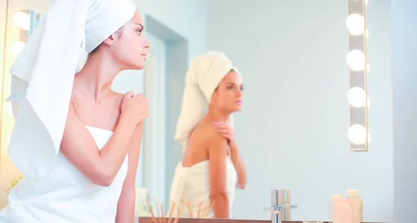 Mujer atractiva joven de pie frente al espejo del baño — Foto de Stock