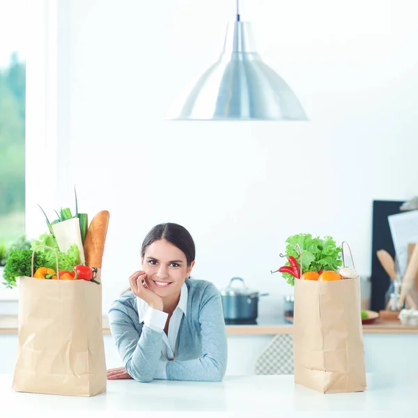 Smiling young woman in the kitchen near desk — Stock Photo, Image