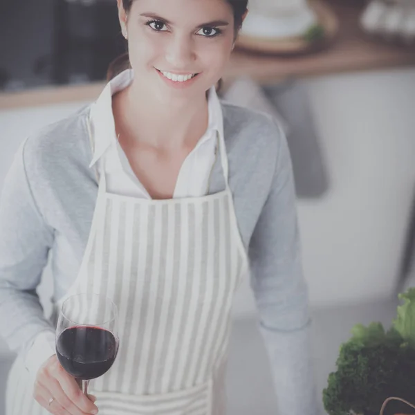 Mujer bonita bebiendo un poco de vino en casa en la cocina — Foto de Stock