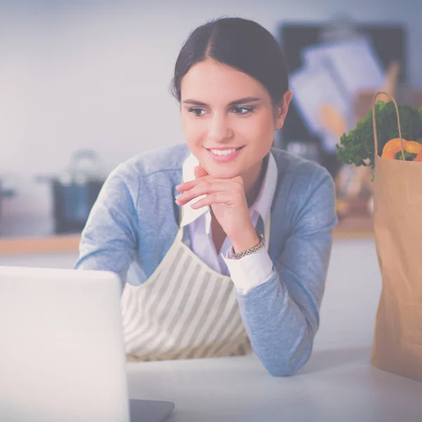 Lachende vrouw online winkelen met behulp van computer en creditcard in de keuken — Stockfoto