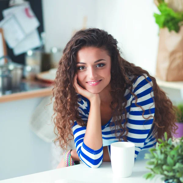 Mujer joven sonriente con portátil en la cocina en casa — Foto de Stock