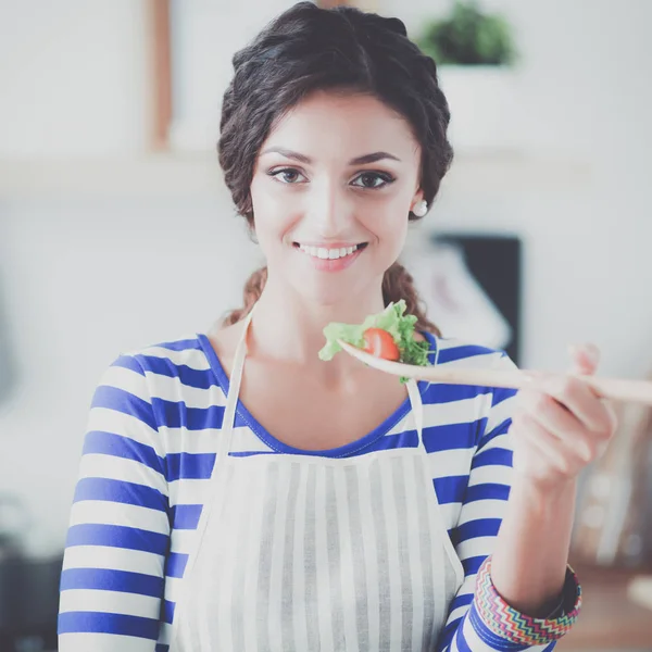 Jovem mulher comendo salada fresca na cozinha moderna — Fotografia de Stock