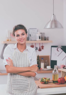 Mutfakta duran gülümseyen genç kadın.