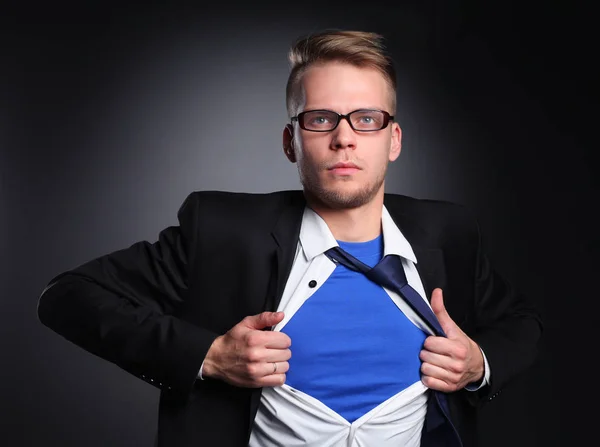 Joven hombre de negocios actuando como un súper héroe y rasgando su camisa, aislado sobre un fondo gris — Foto de Stock