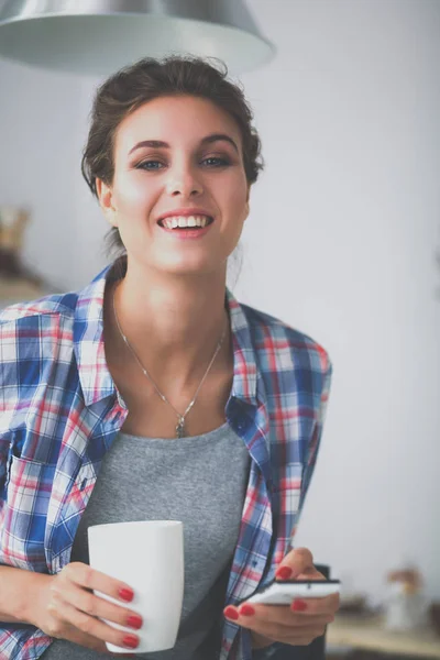 Porträt einer jungen Frau beim Frühstück in der heimischen Küche mit dem Handy — Stockfoto