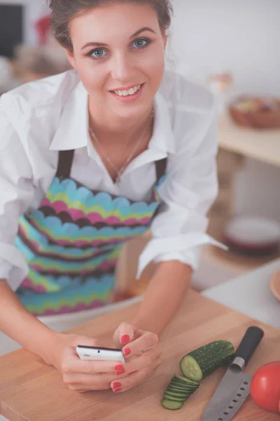 Donna sorridente che tiene il cellulare in cucina — Foto Stock