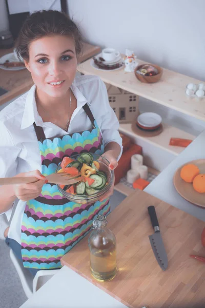Gülümseyen genç kadın mutfakta taze salata karıştırma — Stok fotoğraf
