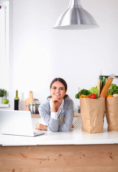Smiling young woman in the kitchen near desk — Stock Photo, Image