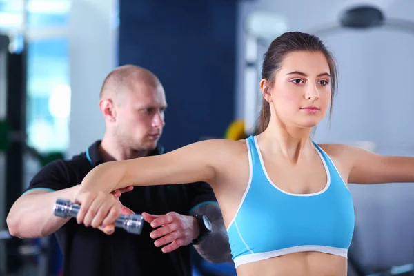 Schöne Frau im Fitnessstudio beim Training mit ihrem Trainer — Stockfoto