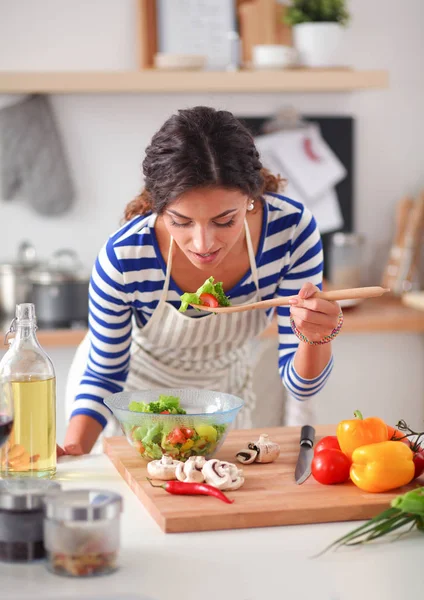 Young woman eating fresh salad in modern kitchen — Stock Photo, Image