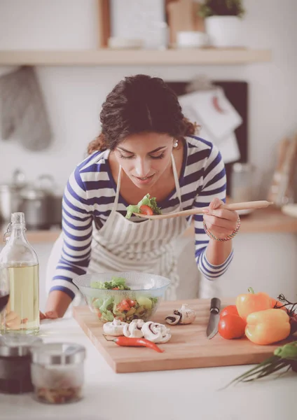 Jovem mulher comendo salada fresca na cozinha moderna — Fotografia de Stock