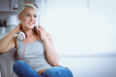 Evdeki genç ve güzel kadın kanepede oturup müzik dinliyor.