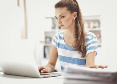 Elinde evrakları olan kadın masanın üstünde oturuyor.