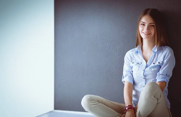暗い壁の近くの床に座っている若い女性 — ストック写真