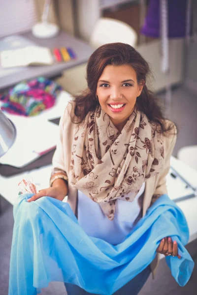 Uśmiechnięta projektantka mody siedzi przy biurku — Zdjęcie stockowe