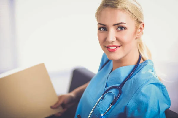 Retrato de un joven médico feliz sentado en el sofá con la carpeta — Foto de Stock