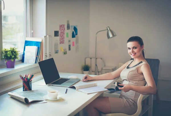 Kvinna med dokument sittande på skrivbordet och laptop — Stockfoto